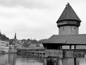 Bridge over river by buildings against sky