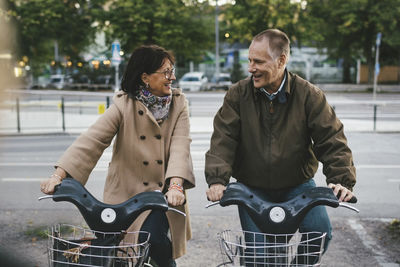 Happy senior couple taking rental bikes at parking lot