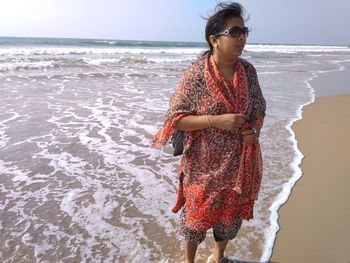 Woman standing on beach against sea