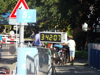 People crossing sign on road in city