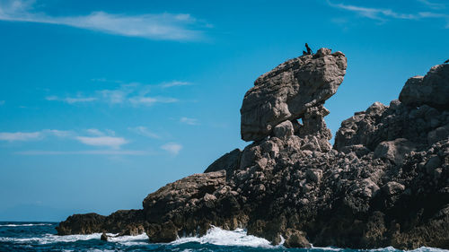 Low angle view of rock formation in sea against sky