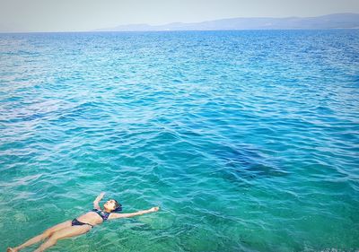 High angle view of carefree woman wearing bikini swimming in sea