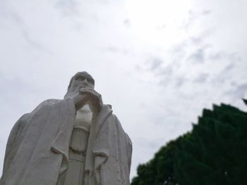 Low angle view of buddha statue against cloudy sky