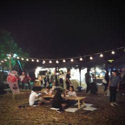 Crowd at illuminated christmas tree in city at night