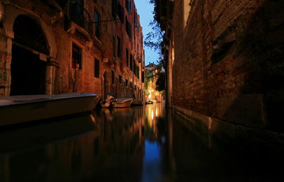 Boats moored in canal along buildings