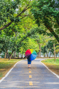 Rear view of woman walking on road during rainy season
