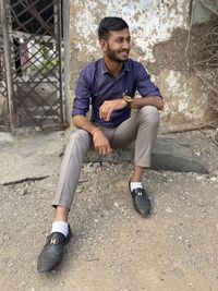 Full length portrait of young man sitting outdoors