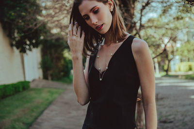 Portrait of young woman standing against tree