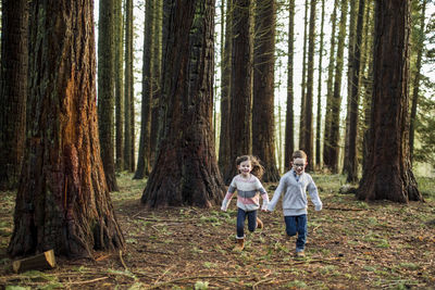 Boy and girl running through trees in the park.