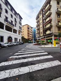 Surface level of road amidst buildings against sky