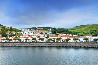 Houses by river against sky in town