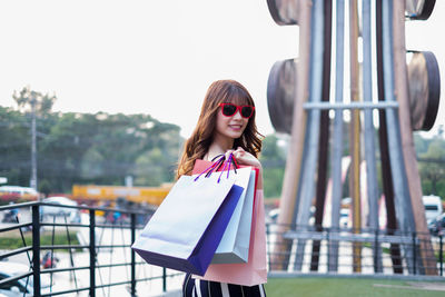 Portrait of young woman holding shopping bags in city
