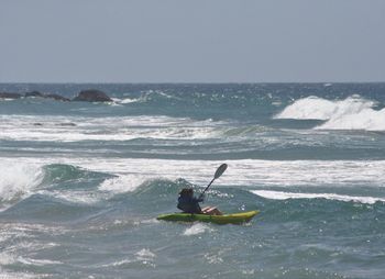 Woman kayaking in sea against clear sky