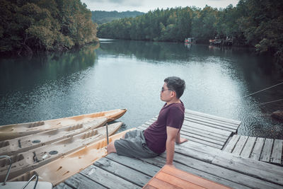 Woman sitting on pier by lake