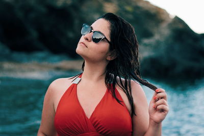 Close-up of woman wearing sunglasses by sea against mountains