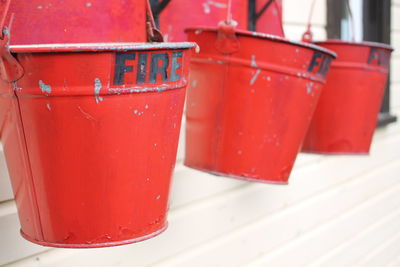 Close-up of red metal buckets with fire text hanging against wall