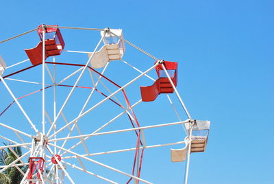 Low angle view of ferris wheel against clear blue sky