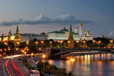 Illuminated buildings by river against sky in city. moscow kremlin