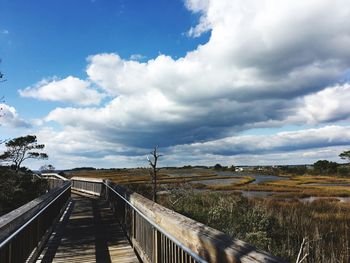 Footbridge over landscape against sky