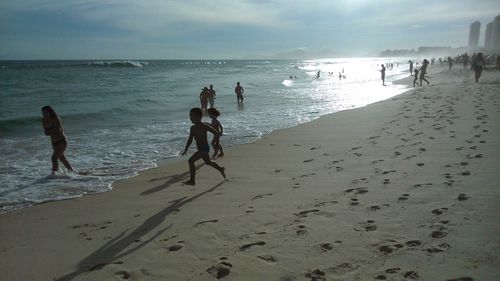People playing on beach against sky