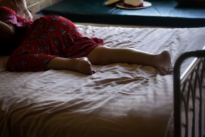 Low section of woman lying on bed at home