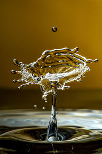 Close-up of drop falling on water against black background