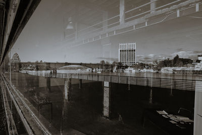 Bridge over river by buildings against sky