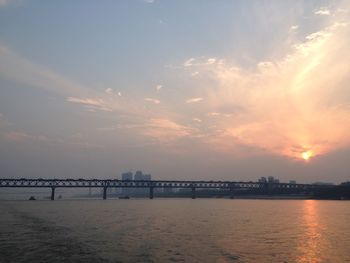 Bridge over river against sky during sunset