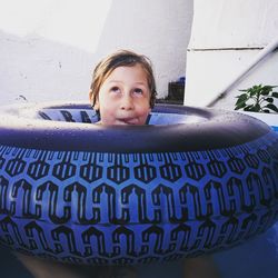 Playful girl sticking out tongue with inflatable ring in swimming pool