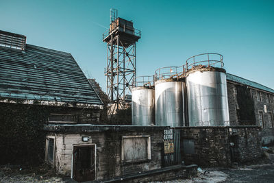 Low angle view of abandoned factory against clear blue sky