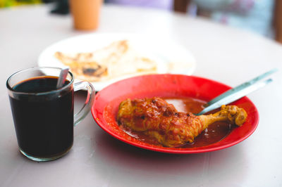 Close-up of meat curry and black coffee on table