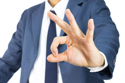 Midsection of businessman gesturing against white background