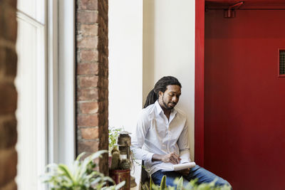 Businessman reading book while sitting in creative office