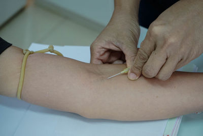 Midsection of doctor injecting syringe to patient hand in hospital