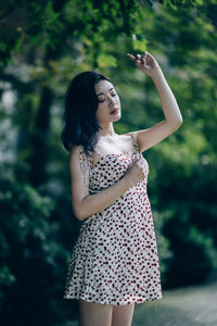 Young woman standing against trees