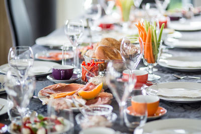 Cold cuts and fruits with vegetables amidst plates on table