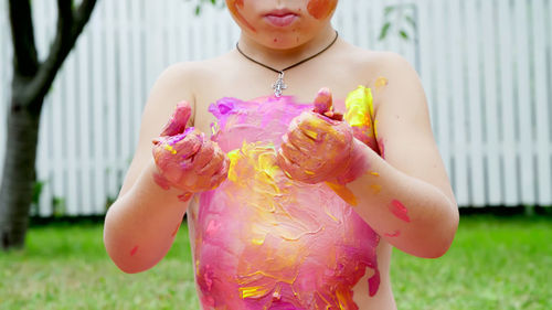 A little child, a four-year-old boy playing, painting with finger paints, decorating himself, in