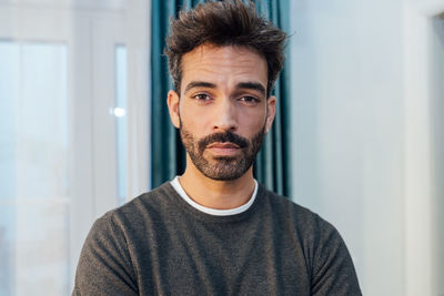 Portrait of young man standing against wall