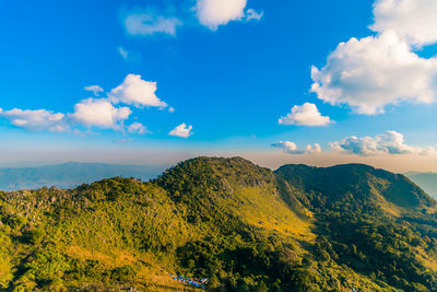 Beautiful green rock mountain range with clear blue sky, clouds, and a base camp