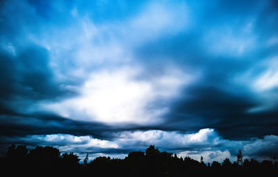 Low angle view of silhouette trees against cloudy sky