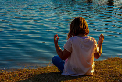 Rear view of woman with arms raised in lake