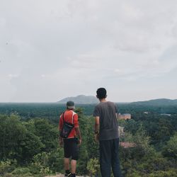 Rear view of men standing against landscape