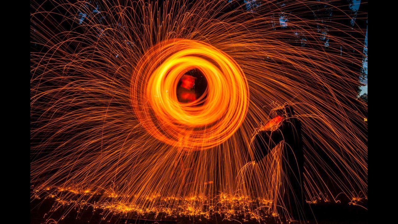 spinning, long exposure, night, wire wool, motion, orange color, illuminated, circle, blurred motion, danger, light painting, speed, burning, light effect, one person, swirl, skill, full length, outdoors, flame, men, real people, fireball, one man only, people