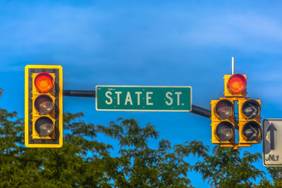 Low angle view of road signal and stoplights against blue sky