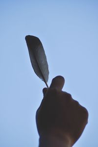 Close-up of hand holding umbrella against clear sky