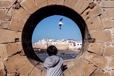 Rear view of boy looking through circular window