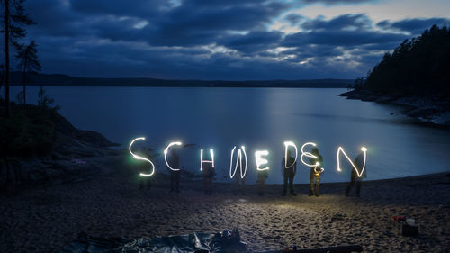 Illuminated lights on beach against sky at sunset