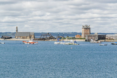 Sailboats in sea against buildings in city