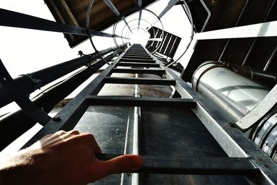 Low angle view of person hand on metallic structure