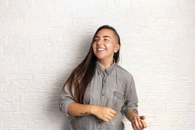 Portrait of smiling young woman standing against wall